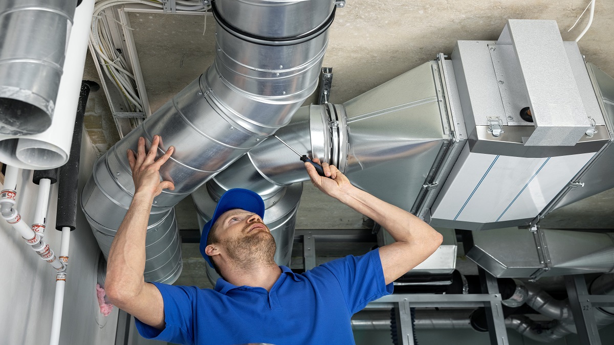 HVAC technician installing formed sheet-metal ventilation ductwork