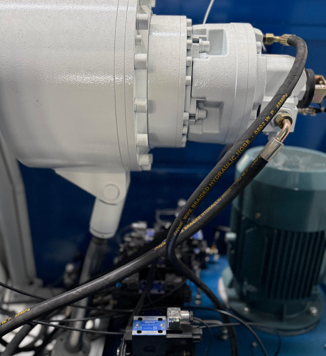 Hydraulic pump motor, valve block and wire-braided hoses on a plate rolling machine
