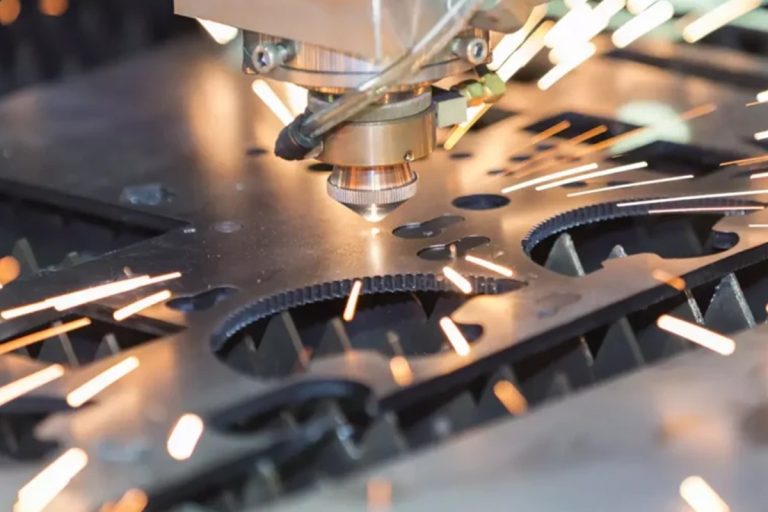 Laser cutting head cutting a metal sheet with sparks above the cutting bed